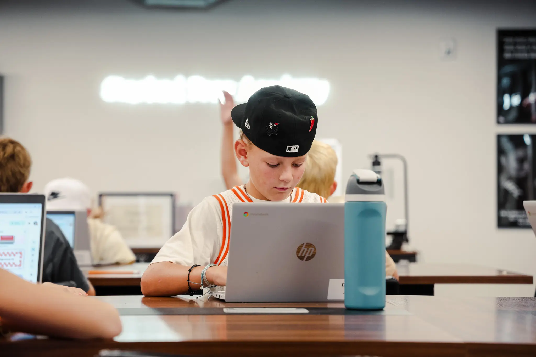 Boy using laptop in classroom setting.